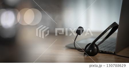 Customer support concept with headset and laptop on wooden desk, symbolizing online communication, helpline assistance, call us service, and professional contact center. Customer support concept with headset and laptop on wooden desk, symbolizing online communication, helpline assistance, call us service, and professional contact center. 130788629