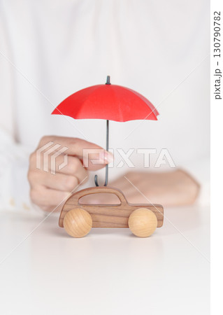 Woman hand holding umbrella and cover car toy on table. Car insurance, warranty, repair, Financial, banking and money concept 130790782