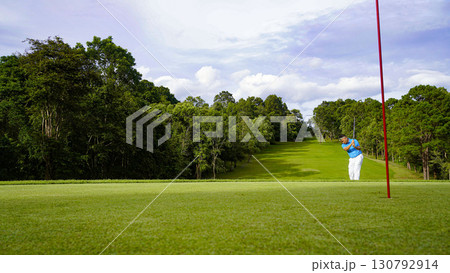 Golfer putting ball on the green golf, lens flare on sun set evening time. Golfer hitting golf ball. 130792914
