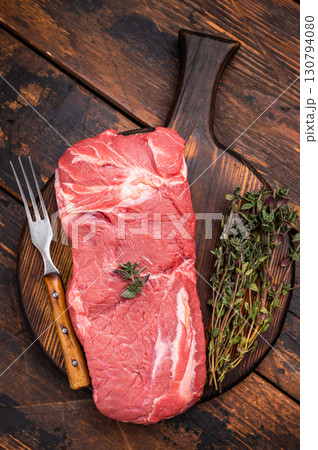 Vibrant raw horse meat on a rustic wooden surface, highlighting its rich color and fine marbling, ideal for unique culinary dishes. wooden background. top view 130794080