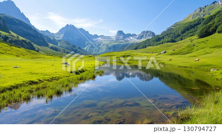 Idyllic alpine landscape reflecting on crystal clear lake with grazing cows 130794727