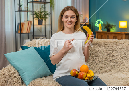 Pregnant woman shows banana vitamin vlog taps belly shares good snack tips during fun baby journey 130794837