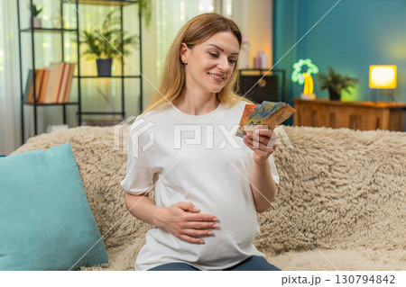 Pregnant woman counts euro cash planning baby birth budget serious money management preparation 130794842