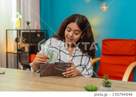 Indian rich woman counting dollars cash placing bills into wallet feeling satisfied, proud wealth 130794846