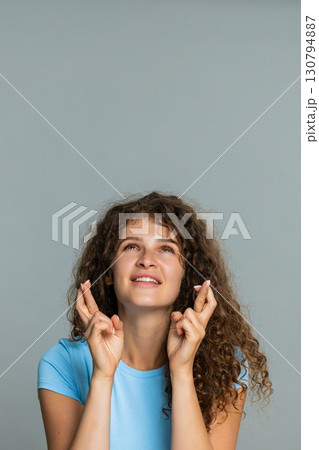 Young woman smiling crossing fingers hoping good luck wish positive optimistic anticipation gesture Young woman smiling crossing fingers hoping good luck wish positive optimistic anticipation gesture 130794887