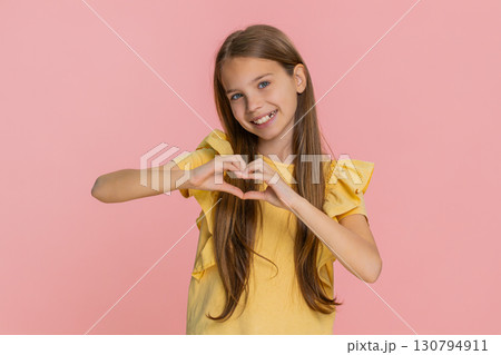 Child girl kid making heart gesture with fingers while smiling to express love friendship emotion Child girl kid making heart gesture with fingers while smiling to express love friendship emotion 130794911
