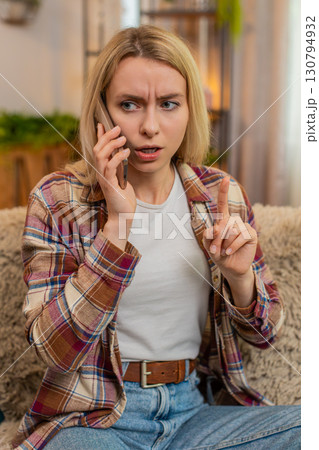 Woman rejecting call on smartphone at home, showing hand gesture to say no with irritated expression Woman rejecting call on smartphone at home, showing hand gesture to say no with irritated expression 130794932