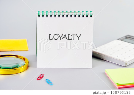 LOYALTY word written in a notebook in a composition with a calculator, a magnifying glass, and stickers. Fake Dictionary, Dictionary definition concept. 130795155