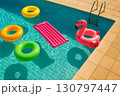 Colorful inflatable pool toys floating in a clear blue swimming pool under bright sunlight 130797447
