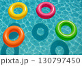 Colorful inflatable pool rings floating on clear water surface creating vibrant summer atmosphere 130797450
