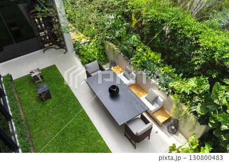 Modern terrace with dining table and chairs. Summer garden space for party. 130800483