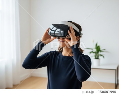 Bright clean room with person wearing VR headset showing curiosity posture reflecting futuristic immersive excitement in simple modern technological lifestyle concept 130801990