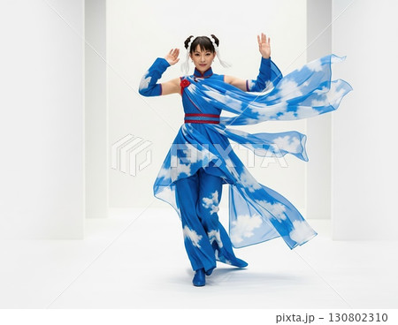 White-background photo of Asian runway contestant wearing a costume shaped like swirling wind, flowing fabrics, and gentle translucent motion 130802310