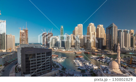 Yachts in Dubai Marina flanked by the Al Rahim Mosque and residential towers and skyscrapers aerial timelapse. 130802829