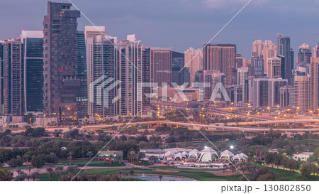 Jumeirah lake towers and Dubai marina skyscrapers and golf course night to day timelapse, Dubai, United Arab Emirates 130802850