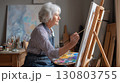 Elderly woman painting on canvas in art studio with focus and creativity 130803755