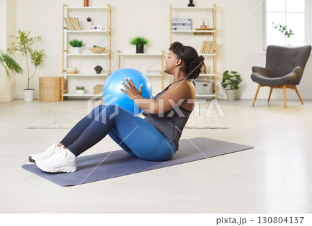 Happy African American Woman Doing Abs Exercises With Fitball At Home 130804137