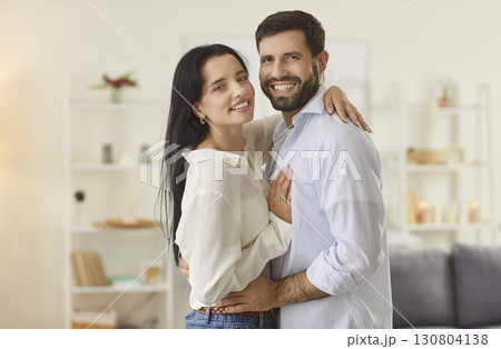 Happy couple embracing as they stand together in their home, radiating love and affection. 130804138