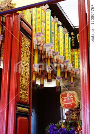 Beautiful of red Chinese Buddhist shrine with Chinese greetings on yellow paper and lamp hanging from the ceiling in front of the entrance wooden red door in Bangkok of Thailand Beautiful of red Chinese Buddhist shrine with Chinese greetings on yellow paper and lamp hanging from the ceiling in front of the entrance wooden red door in Bangkok of Thailand 130804767
