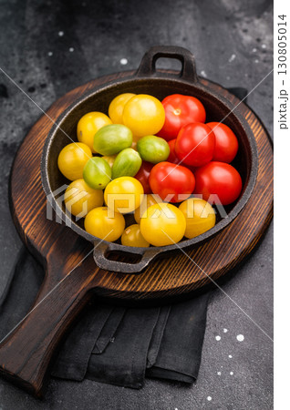 Uncooked small tomatoes. red, green and yellow cherry tomatoes assortment, cocktail mix. black background. top view Uncooked small tomatoes. red, green and yellow cherry tomatoes assortment, cocktail mix. black background. top view 130805014