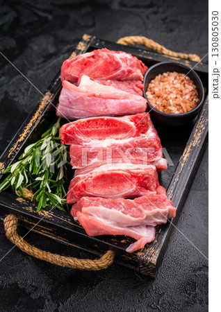 Raw Veal Short Rib, fresh beef meat with bone and herbs for cooking . black background. top view 130805030