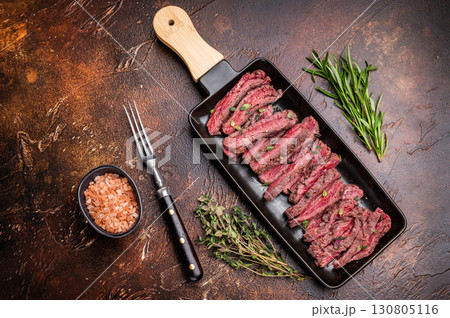 BBQ Grilled Flank beef steak, sliced meat with herbs, brown background. top view BBQ Grilled Flank beef steak, sliced meat with herbs, brown background. top view 130805116