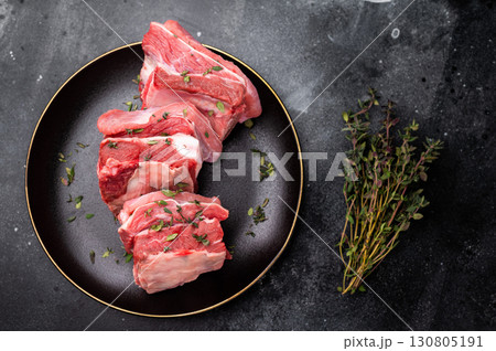 Raw mutton cut rib chops, fresh lamb meat with herbs for grilling. black background. top view Raw mutton cut rib chops, fresh lamb meat with herbs for grilling. black background. top view 130805191
