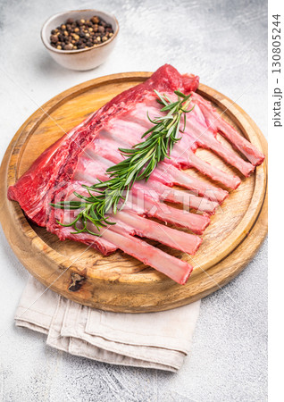 Uncooked rack of lamb, raw mutton chops on wooden board. grey background. top view 130805244