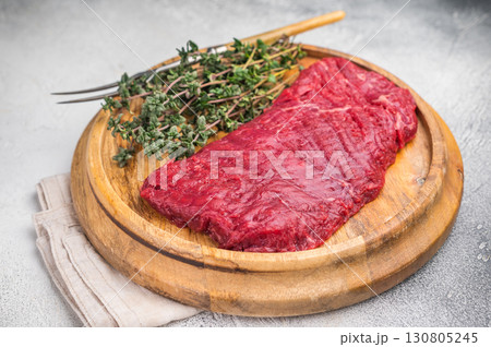 Flank steak, raw beef meat with herbs for frying. grey background. top view Flank steak, raw beef meat with herbs for frying. grey background. top view 130805245