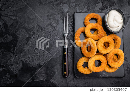 Deep fried squid rings with breading, calamari fastfood snack. black background. top view Deep fried squid rings with breading, calamari fastfood snack. black background. top view 130805407