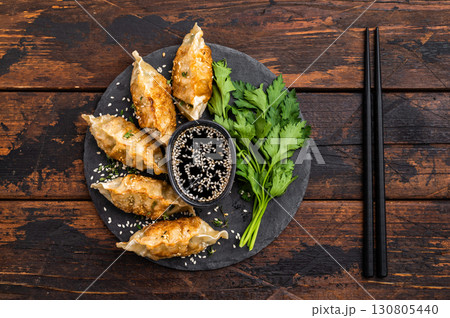 Fried Gyoza on plate with sauce, Japanese Dumplings with shrimps and vegetables. wooden background. top view Fried Gyoza on plate with sauce, Japanese Dumplings with shrimps and vegetables. wooden background. top view 130805440