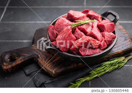 Diced Raw Ostrich meat, uncooked Game Meat in a skillet. black background. top view Diced Raw Ostrich meat, uncooked Game Meat in a skillet. black background. top view 130805446