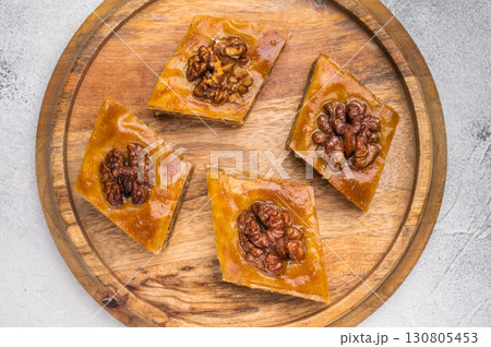 Arabic Traditional Honey Walnut Baklava on wooden board. grey background. top view Arabic Traditional Honey Walnut Baklava on wooden board. grey background. top view 130805453