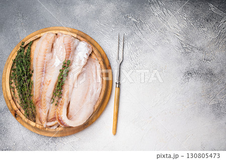 Fresh Raw Hake fish fillets, whitefish meat on a wooden board with herbs. white background. top view 130805473