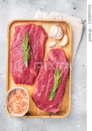 Raw Ostrich steaks, fresh Game Meat in wooden tray. grey background. top view Raw Ostrich steaks, fresh Game Meat in wooden tray. grey background. top view 130805501