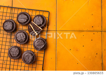 Fresh cooked Jaffa Cookies covered with chocolate and filled with jam on rack. orange background. top view 130805633