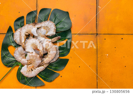 Uncooked Raw white shrimps prawns. Top view. Orange background Uncooked Raw white shrimps prawns. Top view. Orange background 130805656