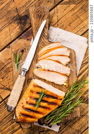 Grilled and sliced Chicken breasts on cutting board, grilled poultry meat, top view, wooden background. 130805687