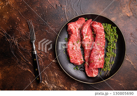 Tri tip steaks, Raw marbled beef meat on plate with herbs. brown background. top view 130805690