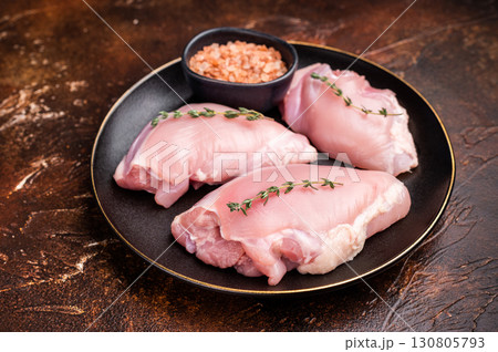Raw Chicken thigh fillet meat, Skinless boneless poultry meat on a plate. brown background. top view 130805793
