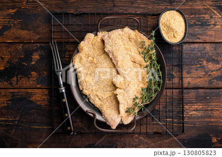 Viennese breaded raw Schnitzel steak on a tray. wooden background. top view 130805823