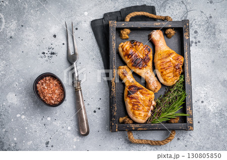 Flavorful chicken drumsticks legs, expertly cooked over an open flame, perfect for serving at family gatherings or picnics. grey background. top view Flavorful chicken drumsticks legs, expertly cooked over an open flame, perfect for serving at family gatherings or picnics. grey background. top view 130805850