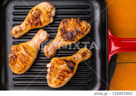 Succulent grilled drumsticks, marinated to perfection and served hot off the grill for a delightful dining experience. orange background. top view Succulent grilled drumsticks, marinated to perfection and served hot off the grill for a delightful dining experience. orange background. top view 130805862