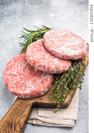 Frozen raw Hamburger beef Patty, uncooked mincemeat. grey background. top view 130805958