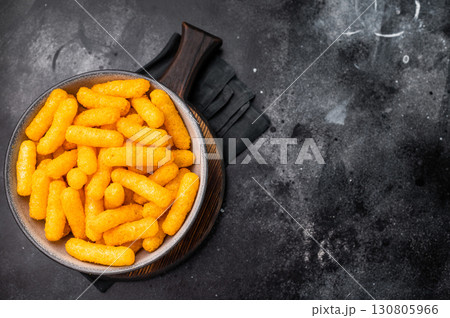 Deliciously addictive cheese flavored corn puffs, beautifully arranged on a plate. black background. top view 130805966