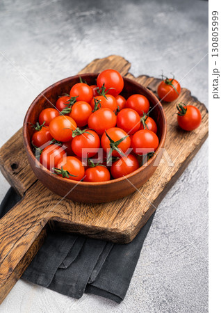 Plump cherry tomatoes, glistening under natural light, highlighting their freshness. Perfect for adding a burst of flavor to any recipe. grey background. top view Plump cherry tomatoes, glistening under natural light, highlighting their freshness. Perfect for adding a burst of flavor to any recipe. grey background. top view 130805999