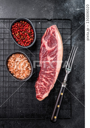 Raw beef picanha steak, featuring a thick layer of fat that adds flavor during cooking. black background. top view 130806020