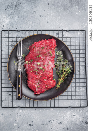 Marinated Skirt machete steak, raw beef meat with thyme and spices on plate. grey background. top view Marinated Skirt machete steak, raw beef meat with thyme and spices on plate. grey background. top view 130806153