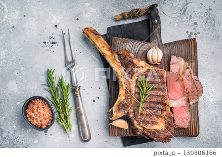 BBQ fried Tomahawk beef steak, grilled marbled rib eye with bone on wooden board. grey background. top view BBQ fried Tomahawk beef steak, grilled marbled rib eye with bone on wooden board. grey background. top view 130806166