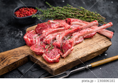 Raw mutton cutlets, fresh lamb meat chops on a wooden board. black background. top view 130806181